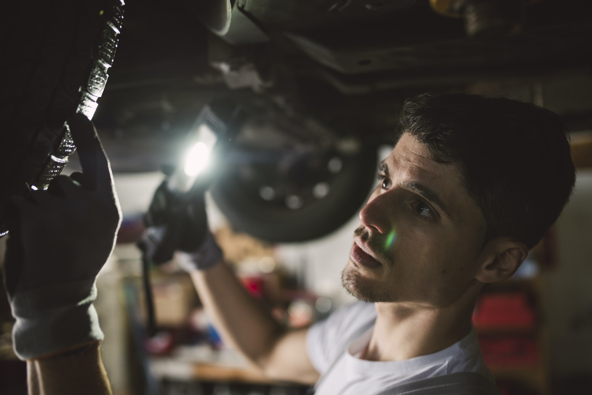 Mechanic checking the underbody of a car in a workshop